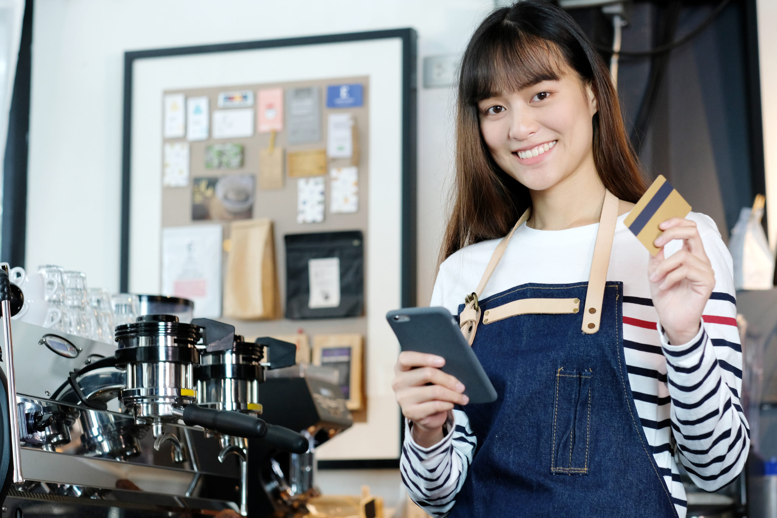 Jeune femme tenant un smartphone et une carte de crédit