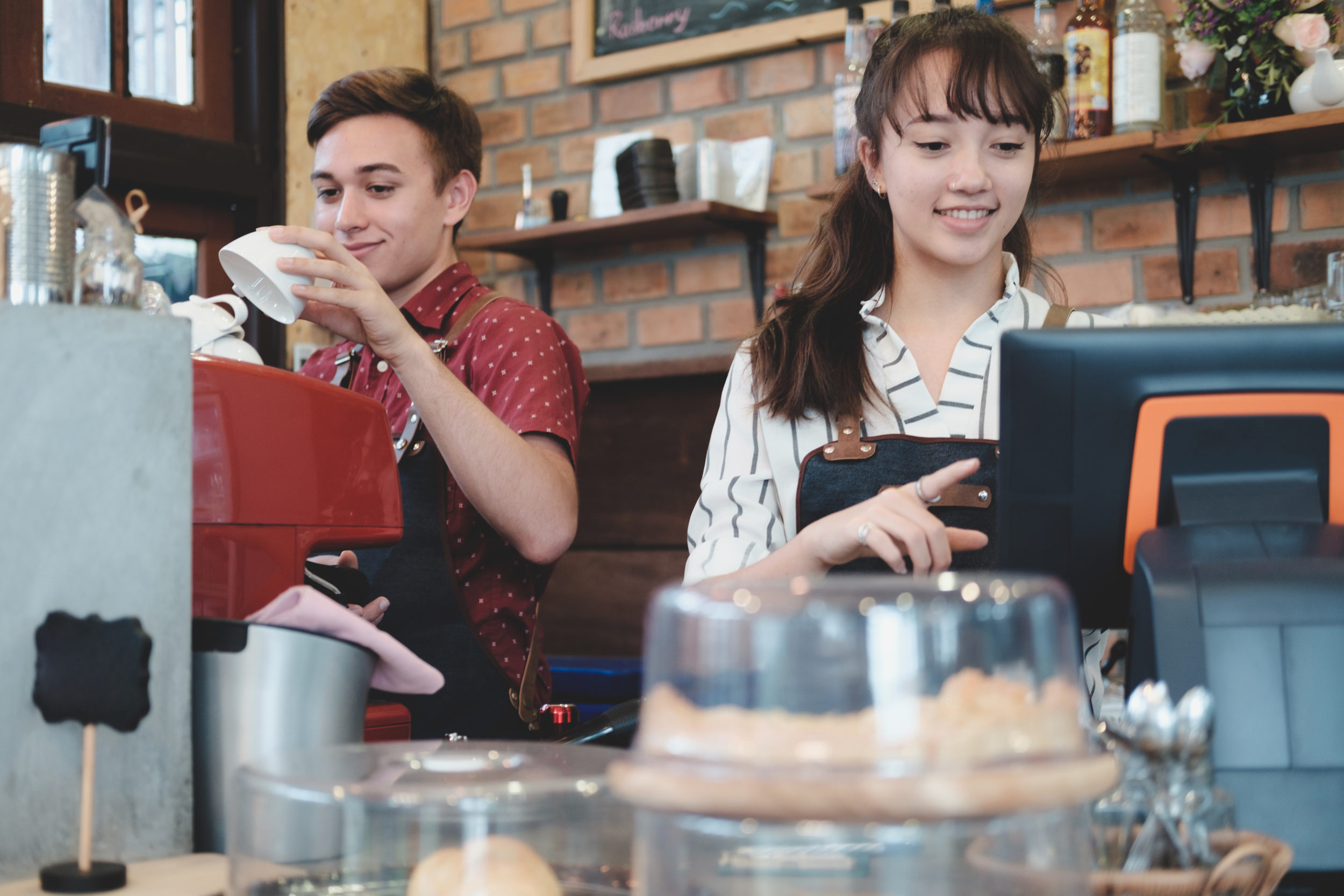 2 serveurs derrière un comptoir utilisant une caisse enregistreuse